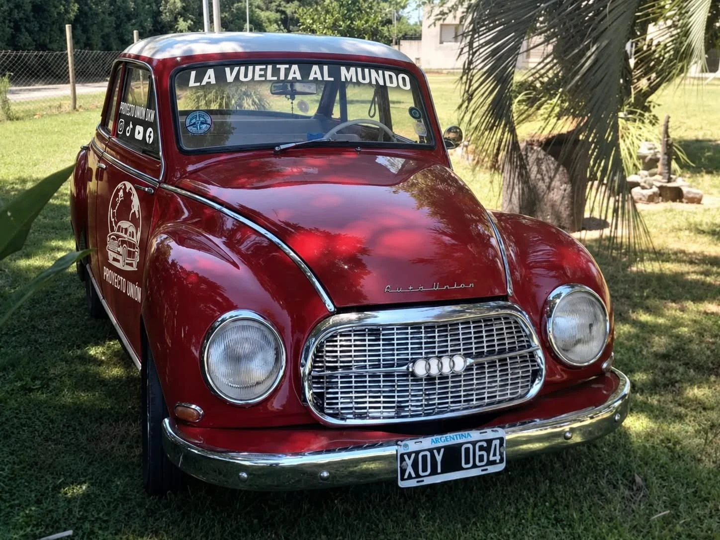 Vista de frente del DKW rojo, con la inscripción La vuelta al mundo en el parabrisas