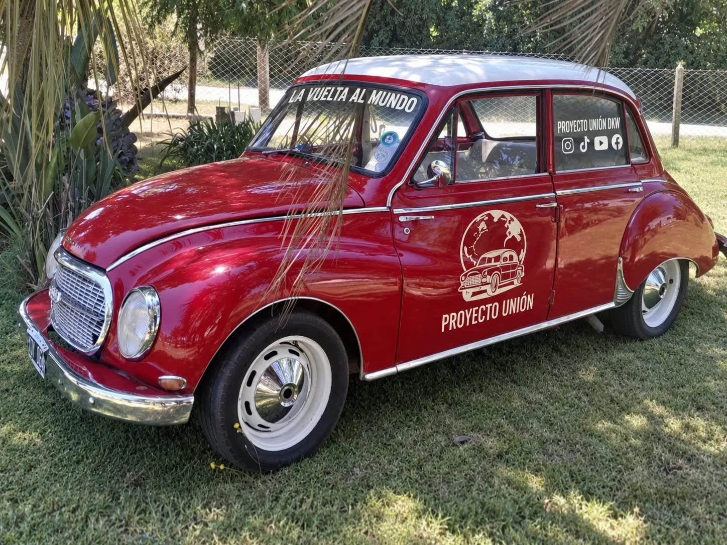 El DKW rojo de Proyecto Unión, con techo blanco y el logo del viaje en su puerta